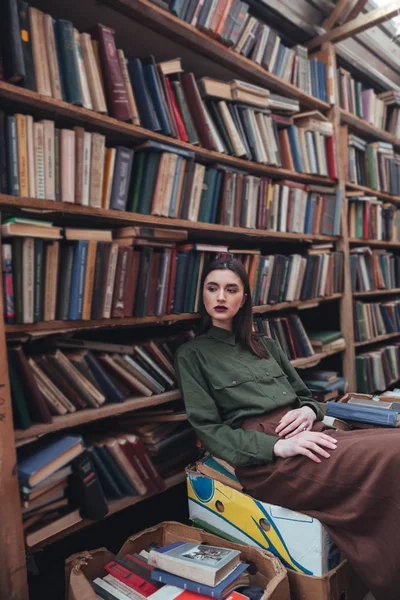 Selbstbewusste Frau sitzt auf Büchern — Stockfoto