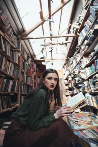 Mulher com livro aberto olhando para o lado — Fotografia de Stock