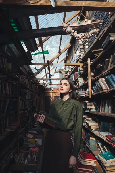 Menina de pé na biblioteca com livros — Fotografia de Stock
