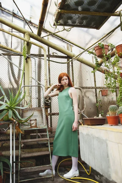 Young pensive girl standing in greenhouse — Stock Photo, Image