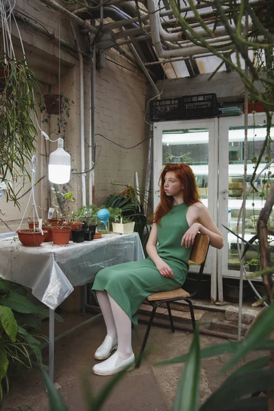 Дівчина сидить на стільці серед рослин — стокове фото