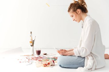 Ciddi genç beyaz Bayan ressam telefon kullanarak çalışma alanı