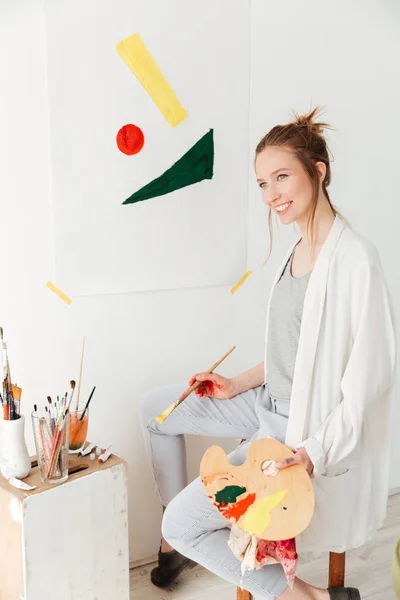 Happy young caucasian lady painter sitting at workspace — Stock Photo, Image