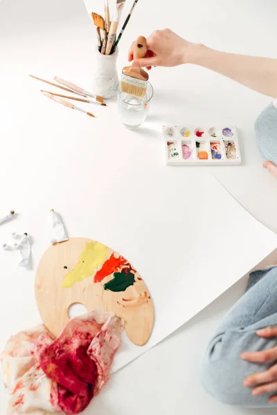 Beskuren bild av ung dam målare sitter på arbetsytan. — Stockfoto