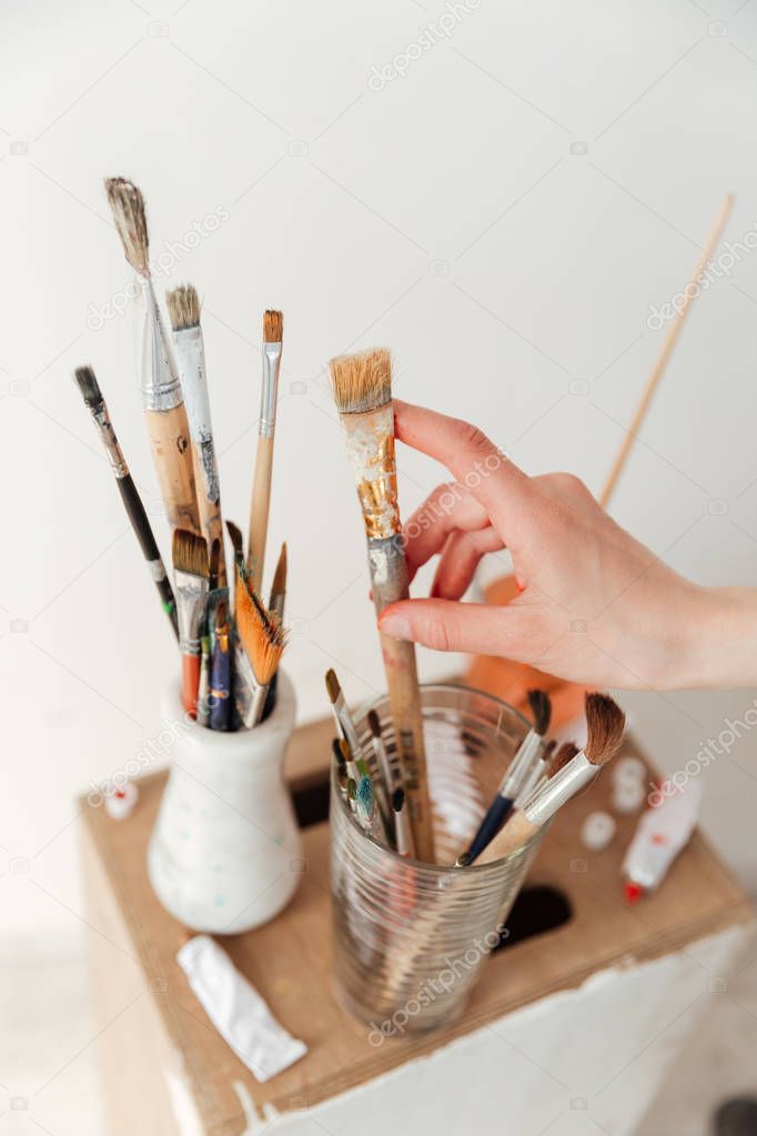 Painting brushes over white wall.