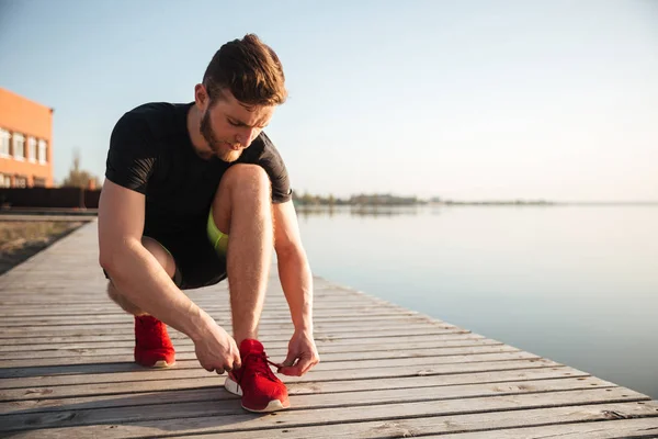 Porträt eines Mannes, der Schnürsenkel an Sportschuhen bindet — Stockfoto