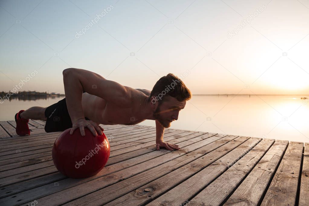 Concentrated young sportsman make sport exercises with ball