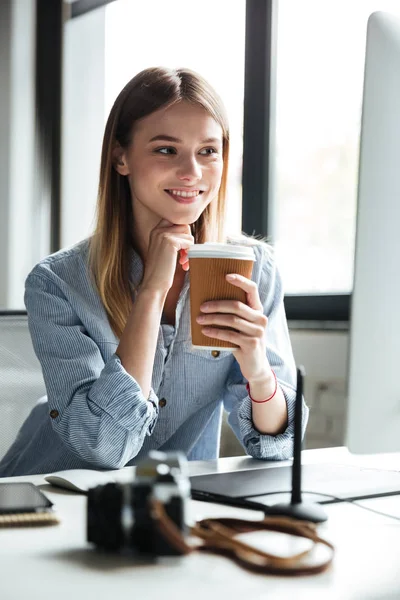 Sorrindo jovem mulher trabalhar no escritório usando computador beber café . — Fotografia de Stock