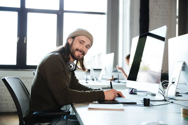 Homem feliz trabalha no escritório usando o computador. Olhando para a câmera . — Fotografia de Stock