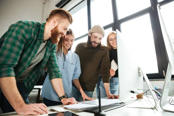 Felices colegas de pie en la oficina usando la computadora — Foto de Stock