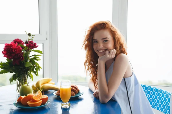 Bella allegra giovane rossa signora vicino a fiori e frutta — Foto Stock