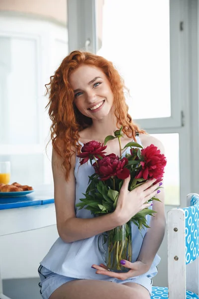 Linda joven pelirroja feliz sosteniendo flores —  Fotos de Stock