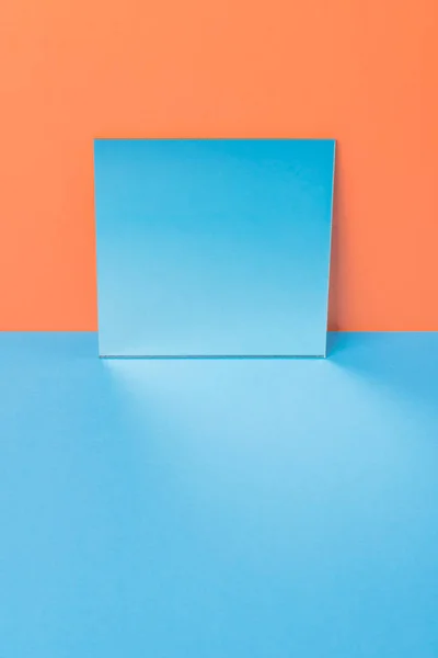 Mirror on blue table isolated over orange background — Stock Photo, Image