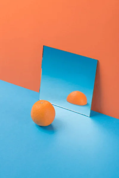 Orange on blue table isolated over orange background — Stock Photo, Image