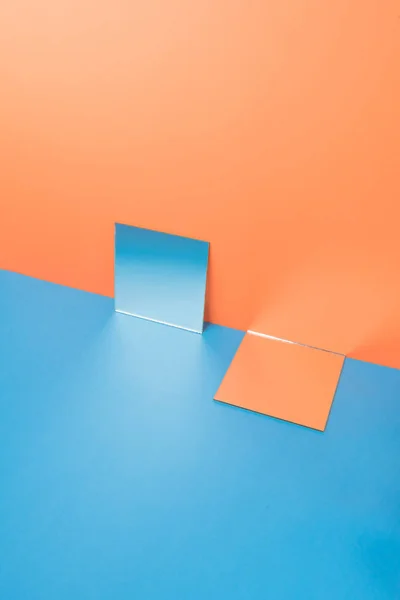 Mirrors on blue table isolated over orange background — Stock Photo, Image
