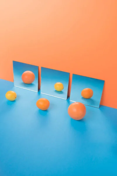 Fruits on blue table isolated over orange background near mirrors — Stock Photo, Image