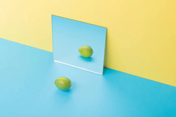 Lipa na niebieski tabeli na białym tle nad żółtym tle w pobliżu lustro — Zdjęcie stockowe