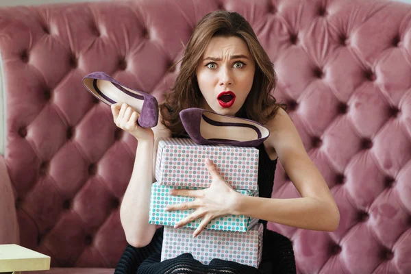 Confused screaming young lady sitting on sofa — Stock Photo, Image