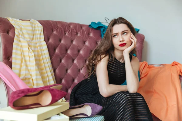 Retrato de uma menina cansada cansada no vestido sentado em um sofá — Fotografia de Stock