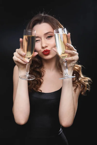 Happy playful woman holding two glasses of champagne and winking — Stock Photo, Image