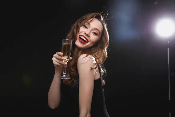 Mujer joven sonriente con labios rojos sosteniendo una copa de champán — Foto de Stock