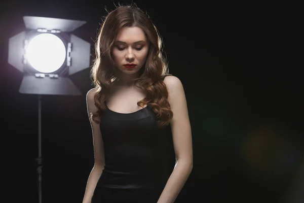 Mooie jonge vrouw in de buurt van studio spotlight — Stockfoto