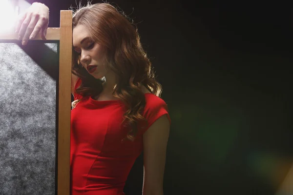 Sensual jovem mulher em vestido vermelho de pé perto da tela dobrável — Fotografia de Stock