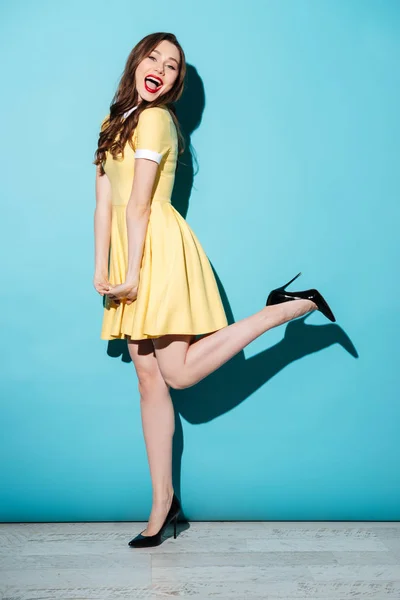 Glückliche junge brünette Frau im gelben Kleid posiert — Stockfoto