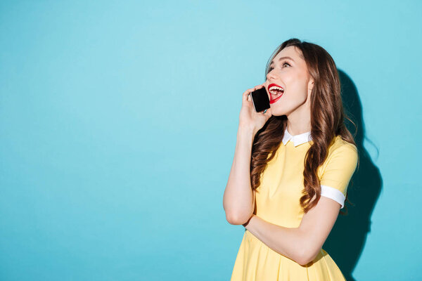 Довольно радостная девушка в платье разговаривает по мобильному телефону
