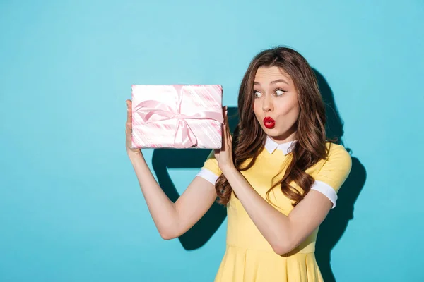 Захоплена молода дівчина в одязі дивиться на подарункову коробку — стокове фото