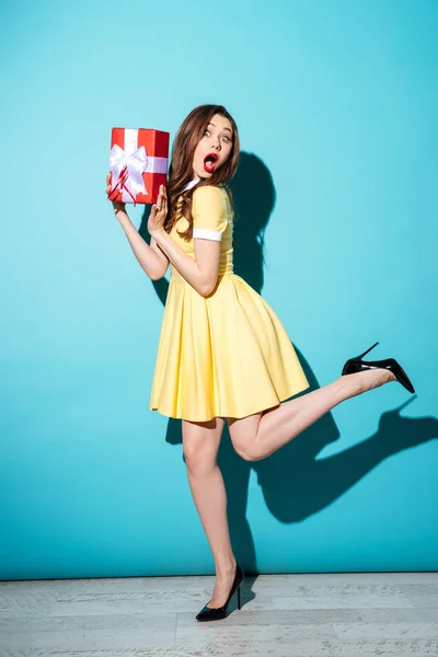 Surprised young brunette woman holding gift. — Stock Photo, Image