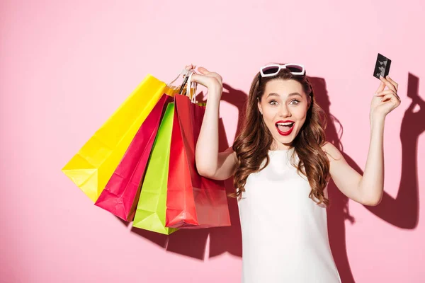 Jovem morena feliz segurando cartão de crédito e sacos de compras — Fotografia de Stock