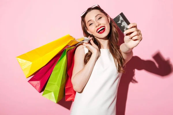 Ευτυχισμένος μελαχρινή νεαρή γυναίκα που κρατώντας πιστωτική κάρτα και τσάντες για ψώνια — Φωτογραφία Αρχείου