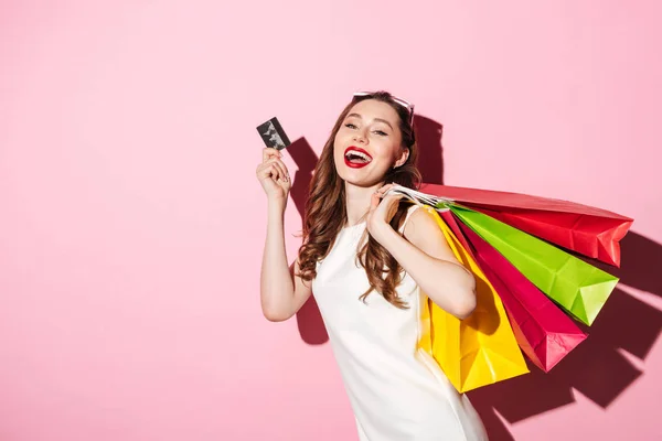 Joven morena alegre sosteniendo tarjetas de crédito y bolsas de compras — Foto de Stock