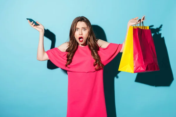 電話と買い物袋を保持している混乱の若いブルネットの女性 — ストック写真