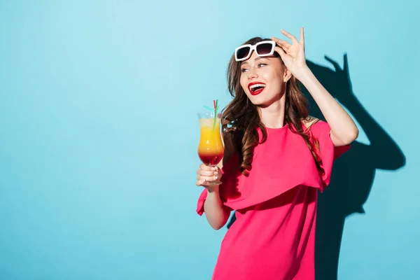Досить усміхнена жінка в сонцезахисних окулярах тримає коктейль і святкує — стокове фото