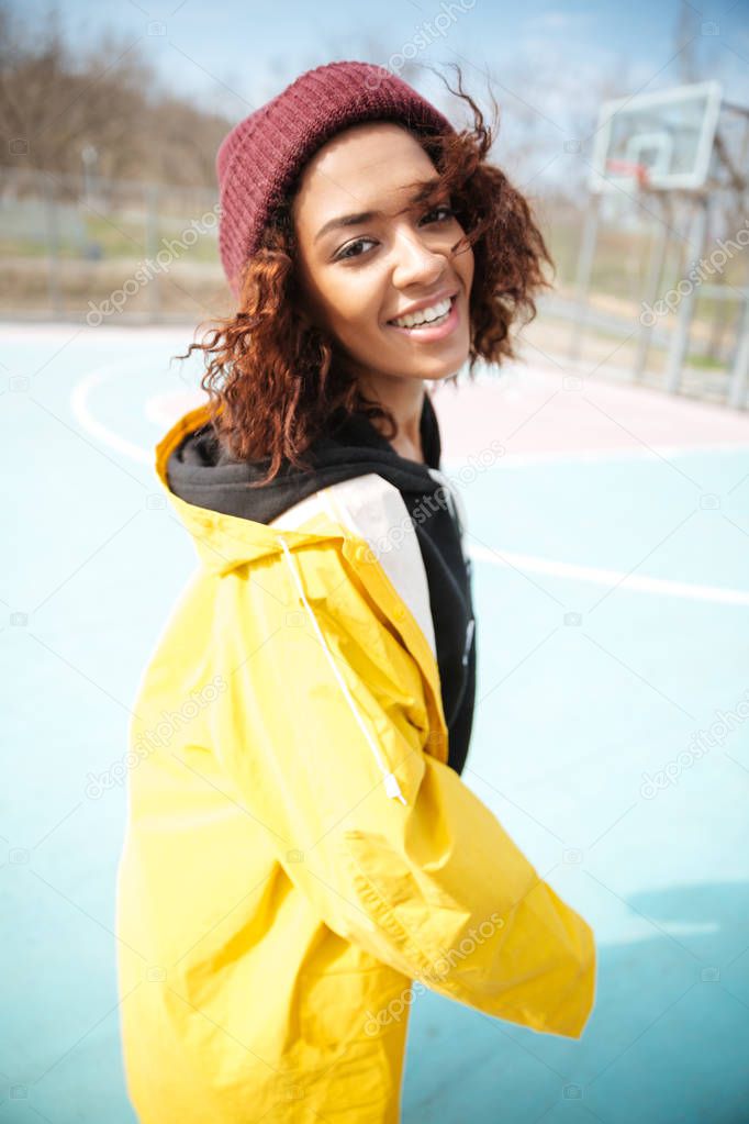 Cheerful african curly young woman wearing yellow coat