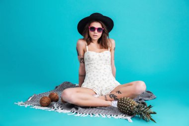 Mavi arka plan üzerinde izole oturan genç ve güzel Bayan