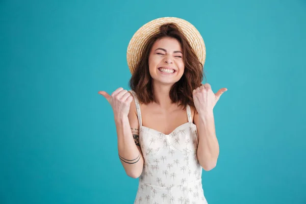 Felice giovane ragazza indossando cappello di paglia e mostrando pollici in su — Foto Stock