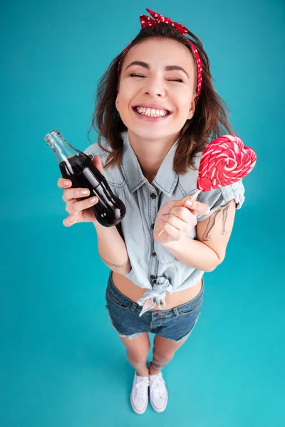 Glückliche junge Frau isst Süßigkeiten und hält belüftetes Süßwasser in der Hand. — Stockfoto