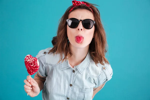 Retrato de una chica divertida y elegante en gafas de sol mostrando la lengua — Foto de Stock