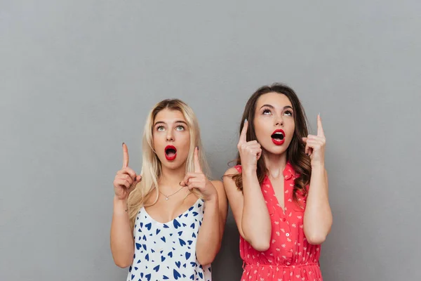 Mujeres jóvenes conmocionadas mirando a un lado y señalando . — Foto de Stock