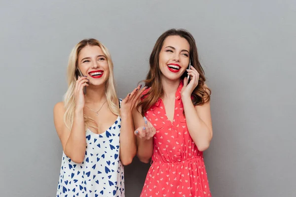 Happy young ladies talking by phones. — Stock Photo, Image