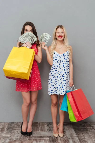 Вертикальне зображення двох жінок, що тримають гроші та сумки — стокове фото