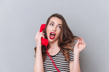 Genç ve güzel Bayan gri duvar telefonla konuşurken üzerinde ayakta