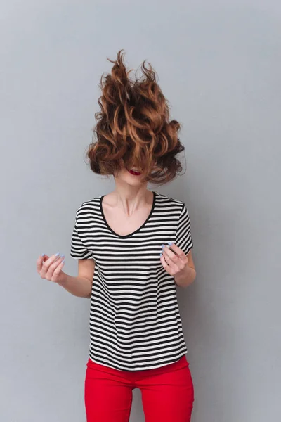 Glad ung dam som står över grå väggen skakar hår. — Stockfoto