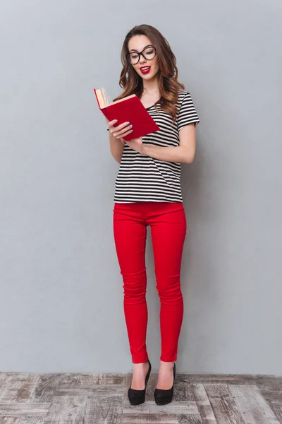 Ευτυχισμένη κοπέλα που στέκεται πάνω από το γκρίζο τοίχο ανάγνωση βιβλίων — Φωτογραφία Αρχείου