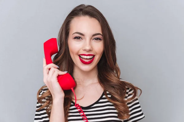 Glad ung dam som står över grå vägg talar via telefon — Stockfoto