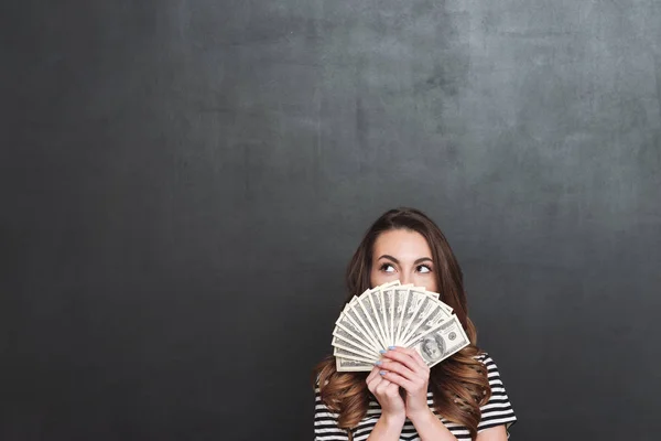 Jovem senhora sobre parede cinza segurando dinheiro nas mãos — Fotografia de Stock