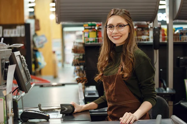 Felice cassiera donna sul posto di lavoro nel negozio di supermercati . — Foto Stock